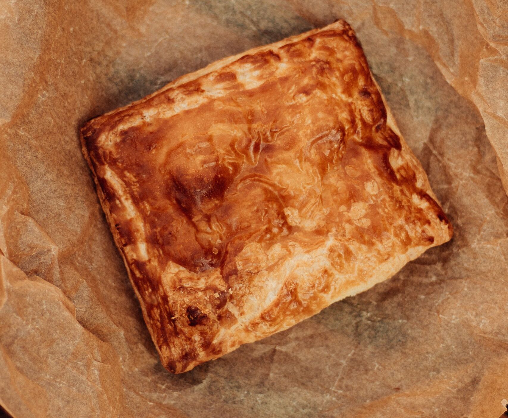 Golden brown baked pastry resting on crumpled parchment paper, showcasing homemade goodness.