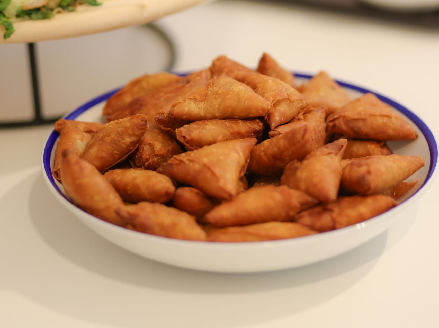 Plate of crispy mini samosas and fresh wraps served on a wooden table in Dubai.